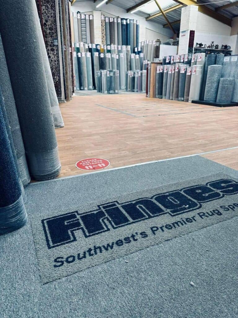 Fringes of Plymouth showroom with rolls and logo mat.